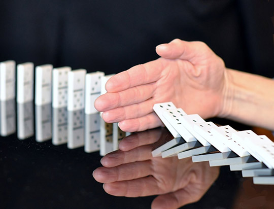 Un homme pose sa main au milieu d'un chemin de dominos pour les arrêter